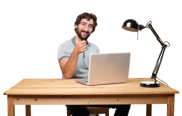 Сумасшедший молодой человек за столом с ноутбуком — стоковое фото