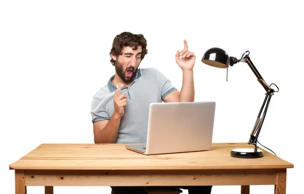 Verrückter junger Mann am Tisch mit Laptop — Stockfoto