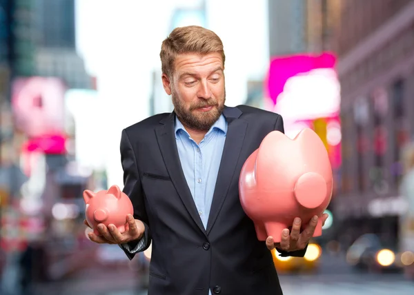 Белокурый бизнесмен с розовыми копилками — стоковое фото