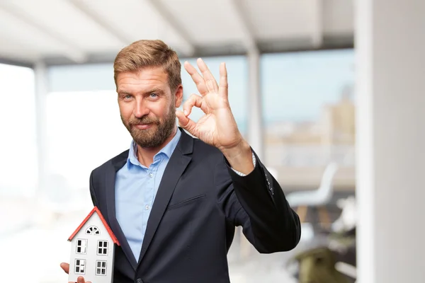 Blonder Geschäftsmann mit Spielzeughaus — Stockfoto