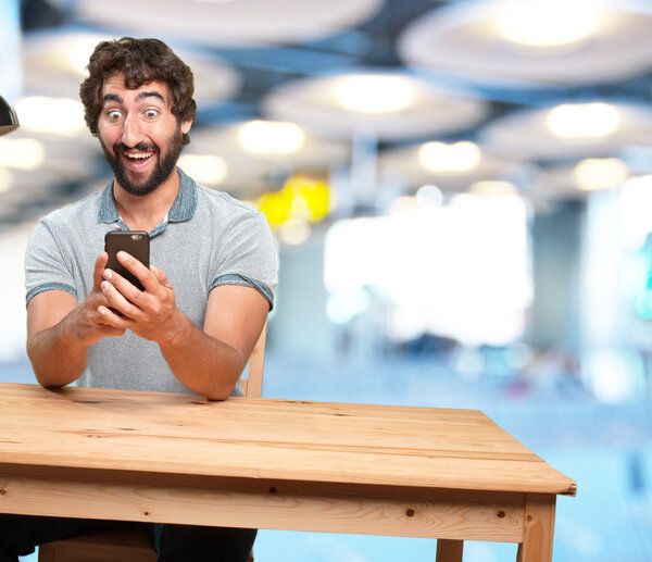 crazy young man at table with mobile phone