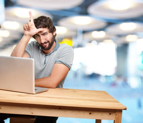 Galen unge mannen vid bordet med laptop — Stockfoto