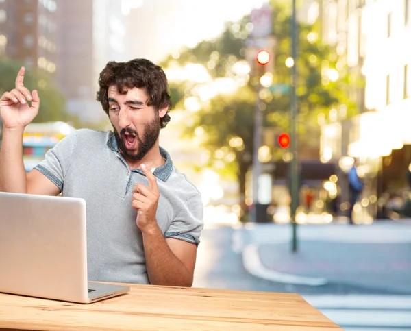 Gek jonge man aan tafel met laptop — Stockfoto