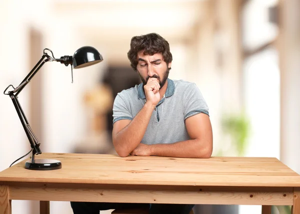 Homem sentado à mesa com expressão irritada — Fotografia de Stock