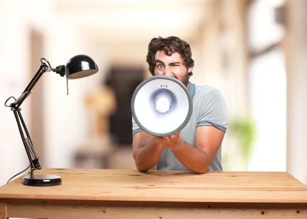 Crazy man sitting at table with megaphone — Stock Photo, Image