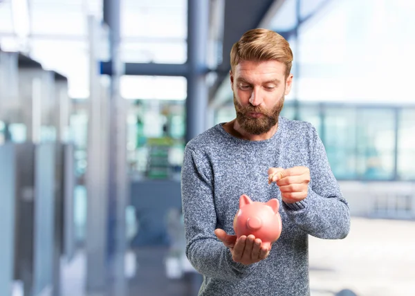 Blonde man met roze spaarpot — Stockfoto