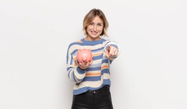 Genç sarışın kadın kameraya bakıyor, kendinden emin, arkadaş canlısı bir gülümsemeyle, seni seçiyor.