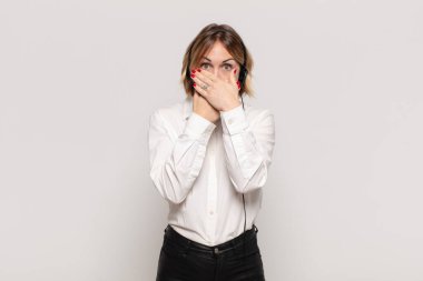 Şok olmuş, şaşırmış bir ifadeyle ağzı kapalı genç sarışın bir kadın sır saklıyor ya da 