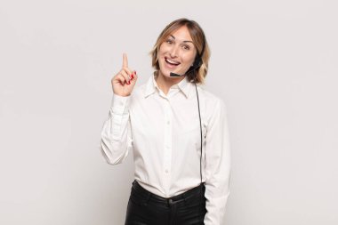 Genç sarışın kadın bir fikri fark ettikten sonra mutlu ve heyecanlı bir dahi gibi hissediyor. Neşeli bir şekilde parmağını kaldırıyor.!