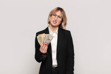 young blonde woman feeling puzzled and confused, with a dumb, stunned expression looking at something unexpected