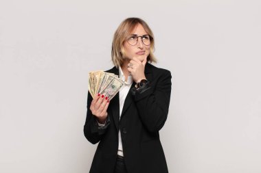 Genç sarışın kadın düşünüyor, kuşkulu ve şaşkın hissediyor, farklı seçeneklerle, hangi kararı vereceğini merak ediyor.