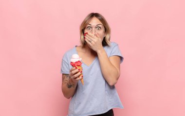 Şok olmuş, şaşırmış bir ifadeyle ağzı kapalı genç sarışın bir kadın sır saklıyor ya da 