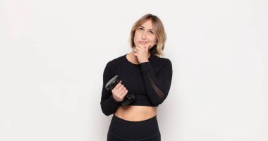 Genç sarışın kadın düşünüyor, kuşkulu ve şaşkın hissediyor, farklı seçeneklerle, hangi kararı vereceğini merak ediyor.