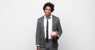 Genç siyah afro adam şaşkın ve kafası karışmış görünüyor, gergin bir hareketle dudağını ısırıyor, sorunun cevabını bilmiyor.