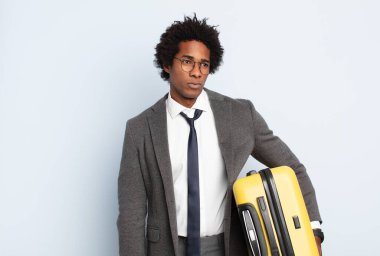 Genç siyah afro adam üzgün, üzgün ya da kızgın ve olumsuz bir tavırla, anlaşmazlık içinde somurtuyor.