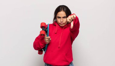 Genç İspanyol kadın kızgın, sinirli, hayal kırıklığına uğramış ya da canı sıkkın, ciddi bir bakışla başparmağını kaldırıyor.