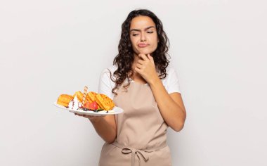 Genç İspanyol kadın düşünüyor, kuşkulu ve şaşkın hissediyor, farklı seçeneklerle, hangi kararı vereceğini merak ediyor.