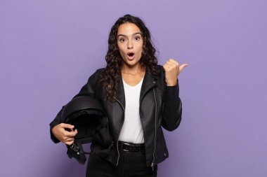 Genç İspanyol kadın inançsızlıktan şaşkın şaşkın bakıyor, yan taraftaki objeyi işaret ediyor ve diyor ki: