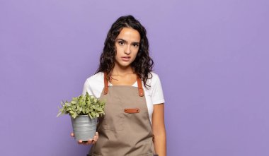 young hispanic woman feeling puzzled and confused, with a dumb, stunned expression looking at something unexpected