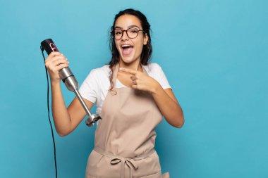 Genç İspanyol kadın heyecanlı ve şaşırmış görünüyor. Yan tarafı işaret ediyor ve uzayı kopyalıyor.