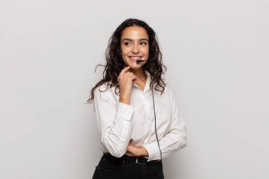 Genç İspanyol kadın mutlu bir şekilde gülümsüyor ve hayal kuruyor ya da şüphe ediyor.