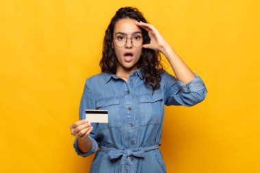 Genç İspanyol kadın mutlu, şaşkın ve şaşırmış görünüyor, gülümsüyor ve inanılmaz ve inanılmaz iyi haberleri fark ediyor.