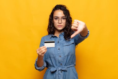 Genç İspanyol kadın kızgın, sinirli, hayal kırıklığına uğramış ya da canı sıkkın, ciddi bir bakışla başparmağını kaldırıyor.