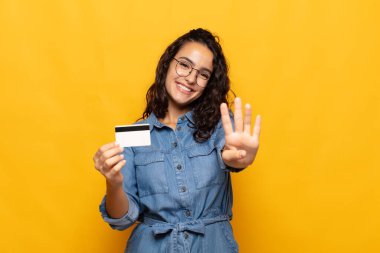 Genç İspanyol kadın gülümsüyor ve arkadaş canlısı görünüyor. Elleri önde, geriye doğru sayıyor.