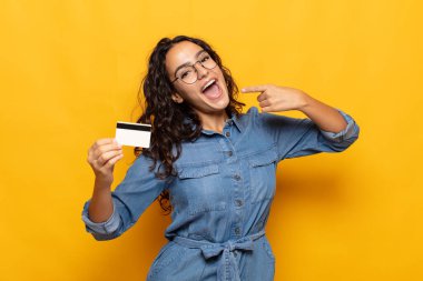 Genç İspanyol kadın kendine güvenerek gülümsüyor. Geniş gülümseme, pozitif, rahat, tatmin olmuş tavır.