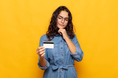 Genç İspanyol kadın düşünüyor, kuşkulu ve şaşkın hissediyor, farklı seçeneklerle, hangi kararı vereceğini merak ediyor.