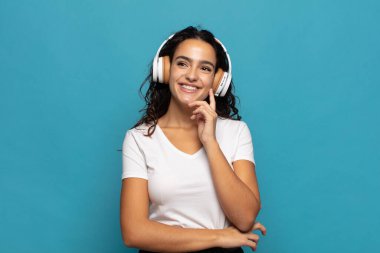 Genç İspanyol kadın mutlu bir şekilde gülümsüyor ve hayal kuruyor ya da şüphe ediyor.