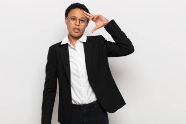 Genç siyah afro kadın mutlu, şaşkın ve şaşırmış görünüyor, gülümsüyor ve inanılmaz ve inanılmaz iyi haberleri fark ediyor.