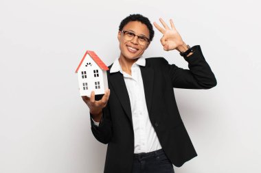 Genç siyah afro kadın mutlu, rahat ve tatmin olmuş hissediyor. Onayını iyi bir hareketle gösteriyor. Gülümsüyor.