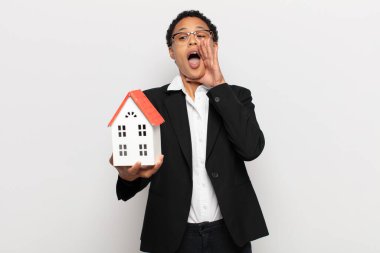 Genç siyah afro kadın mutlu, heyecanlı ve pozitif hissediyor, elleri ağızlarının yanında bağırıyor, bağırıyor