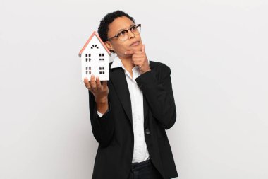 Genç siyah afro kadın düşünüyor, kuşkulu ve şaşkın hissediyor, farklı seçeneklerle, hangi kararı vereceğini merak ediyor.