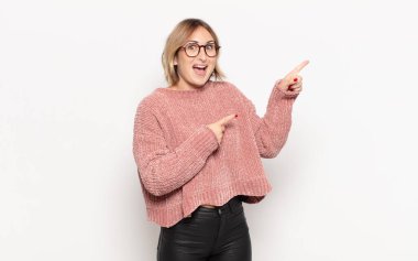 Genç ve güzel bir kadın şaşkın bir ifadeyle gülümsüyor ve bir tarafı işaret ediyor.