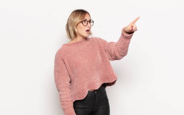 Genç, güzel bir kadın şaşkın ve şaşırmış hissediyor. Şaşırmış ve ağzı açık bir şekilde hayranlıkla yukarı bakıyor.