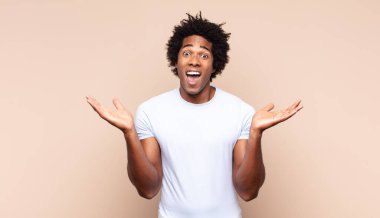 Genç siyah afro adam şok olmuş ya da şaşırmış görünüyor, ağzı açık bir şekilde 