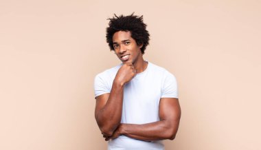 Genç siyah afro adam son derece mutlu ve şaşırmış görünüyor, başarıyı kutluyor, bağırıyor ve zıplıyor.