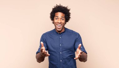 Genç siyah afro adam kendini mutlu, havalı, tatmin olmuş, rahat ve başarılı hissediyor, kameraya bakıyor, seni seçiyor.