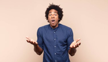 Genç siyah afro adam öfkeyle bağırıyor, stresli ve elleri havada neden ben diye bağırıyor.