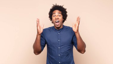 Genç siyah afro adam şok olmuş, kızgın, sinirli ya da hayal kırıklığına uğramış, ağzı açık ve öfkeli görünüyor.