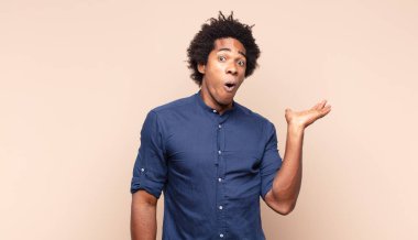 Genç siyah afro adam mutlu, şaşırmış ve neşeli hissediyor, olumlu bir tavırla gülümsüyor, bir çözüm ya da fikri fark ediyor.