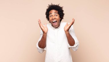 Genç siyah afro adam şok olmuş ve heyecanlı, gülüyor, şaşırmış ve mutlu çünkü beklenmedik bir sürpriz