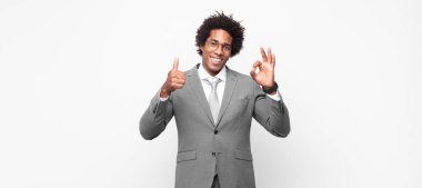 Siyah afro iş adamı mutlu, şaşkın, tatmin olmuş ve şaşırmış hissediyor, tamam gösteriyor ve iyi hareketler yapıyor, gülümsüyor
