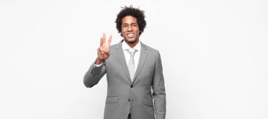 Siyah afro iş adamı gülümsüyor ve arkadaş canlısı görünüyor, üç ya da üç numarayı gösteriyor, eli önde, geri sayıyor.