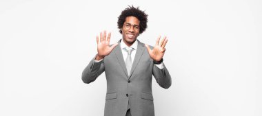 Siyah afro iş adamı gülümsüyor ve dost canlısı görünüyor, 9 ya da 9 numarayı gösteriyor, eli önde, geriye doğru sayıyor