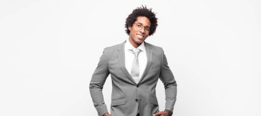 Siyah afro iş adamı neşeli bir şekilde gülümsüyor. Olumlu, mutlu, kendinden emin ve rahat bir ifadeyle.