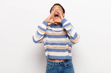 Afro genç siyahi kadın mutlu, heyecanlı ve pozitif hissediyor, elleri ağızlarının yanında bağırıyor, bağırıyor