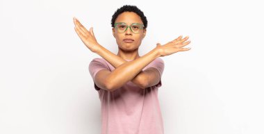 Afro genç siyahi kadın senin tavırlarından rahatsız ve bıkkın görünüyor, yeter artık! Eller önde çapraz, durmanı söylüyor.